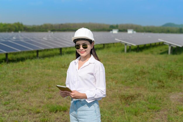 Una ingeniera con casco en una granja de células fotovoltaicas o en un campo de paneles solares