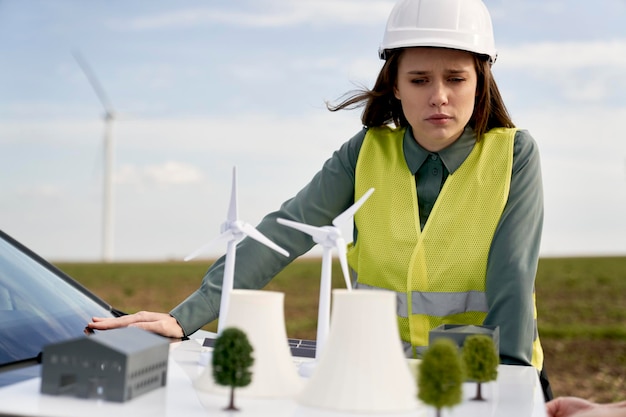 Foto ingeniera caucásica de pie al aire libre y comprobando el modelo de plástico del campo de la turbina eólica