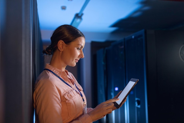 Ingeniera caucásica que usa tableta digital en la sala de servidores de computadoras. concepto de gestión y mantenimiento del servidor de bases de datos