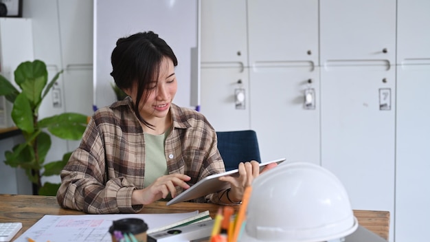 Ingeniera de obras de construcción que trabaja con una tableta digital en una oficina moderna