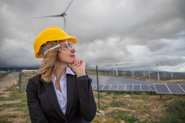 Una ingeniera pensativa en una planta de energía solar durante una foto de inspección con espacio para copiar