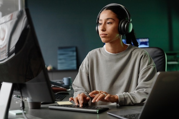 Ingeniera de TI de Oriente Medio en auriculares codificando en computadora en la oficina