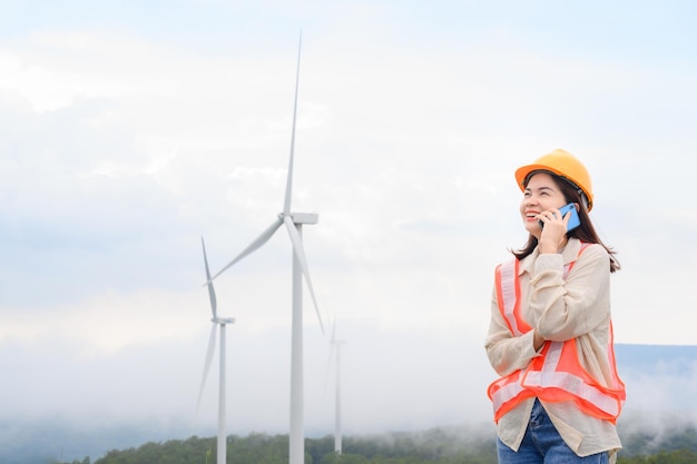 Ingeniera trabajadora Inspeccionar turbinas eólicas y el progreso de la inspección de turbinas eólicas en la estación de generación de energía renovable Discutir el trabajo por teléfono