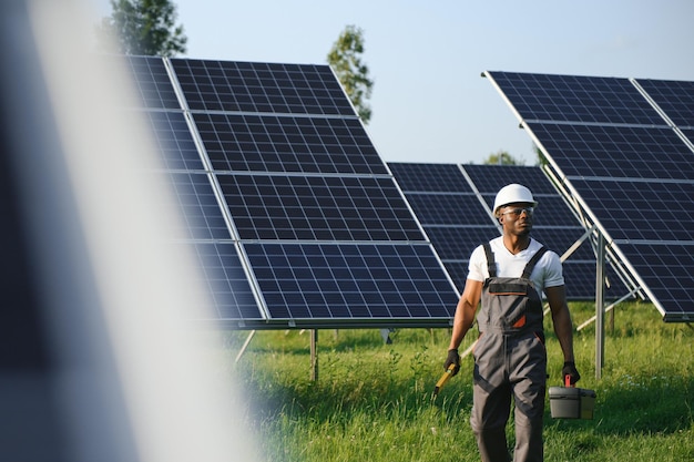 Ingeniero afroamericano que mantiene paneles de células solares Técnico que trabaja al aire libre en la construcción de granjas solares ecológicas Concepto de tecnología de energía limpia renovable