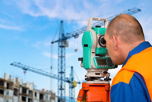 Ingeniero agrimensor trabajando con teodolito en segundo plano.