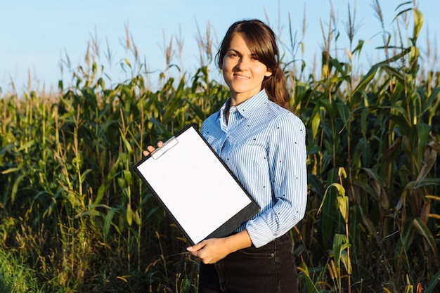 Ingeniero agrónomo de hermosa chica con cuaderno y analiza la cosecha de maíz