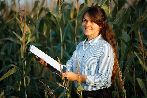 Ingeniero agrónomo de hermosa chica con cuaderno y analiza la cosecha de maíz