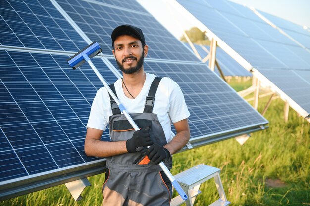 Ingeniero árabe de pie en el campo con filas de paneles solares