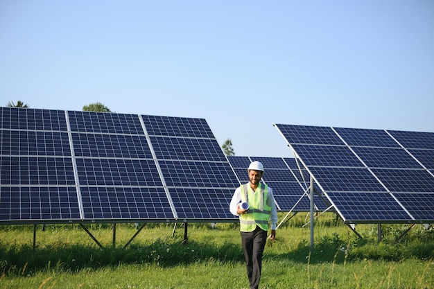 Ingeniero árabe de pie en un campo con filas de paneles solares