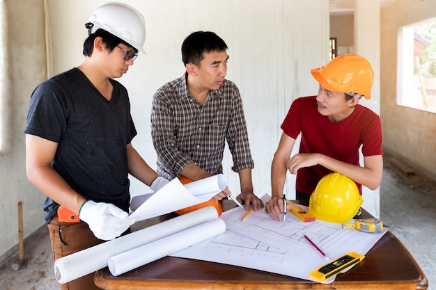 Ingeniero y arquitecto que discuten con el capataz en emplazamiento de la obra.