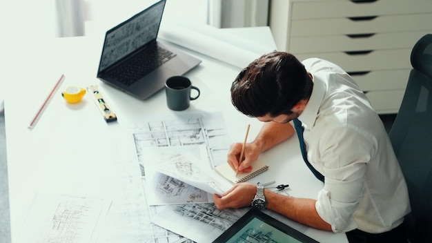 Ingeniero arquitecto que utiliza una computadora portátil para planificar el diseño de la casa en la alimentación de la oficina