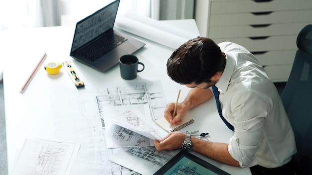 Ingeniero arquitecto que utiliza una computadora portátil para planificar el diseño de la casa en la alimentación de la oficina