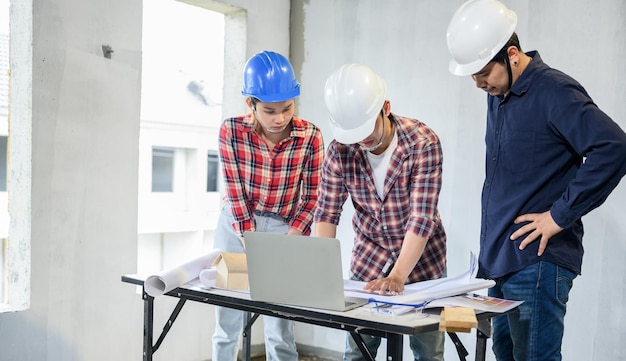 Ingeniero y arquitectos trabajando y discutiendo en el sitio de construcción. Inspección del propietario en el proyecto de la aldea y la construcción de fincas.