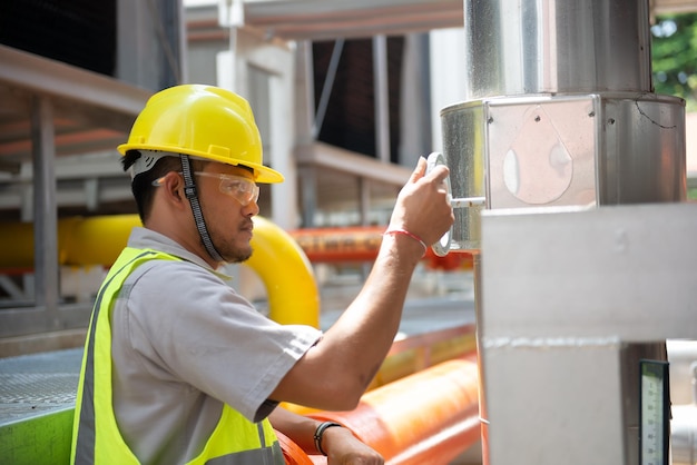 Ingeniero asiático con gafas trabajando en el mantenimiento de la sala de calderas comprobando los datos técnicos del equipo del sistema de calefacciónGente tailandesa