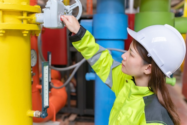 Ingeniero asiático con gafas trabajando en el mantenimiento de la sala de calderas comprobando los datos técnicos del equipo del sistema de calefacciónGente tailandesa