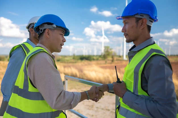 Ingeniero asiático que trabaja en el trabajo de campo al aire libre Los trabajadores revisan e inspeccionan la construcción y la máquina alrededor del sitio del proyecto de construcción Turbina eólica para electricidad de energía limpia y medio ambiente sostenible