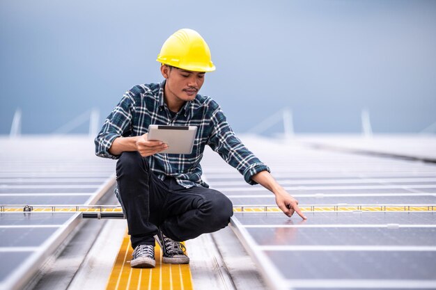 Ingeniero asiático que usa tableta para verificar el sistema de energía solar para controlar la ecología industrial en la fábrica de techo superior