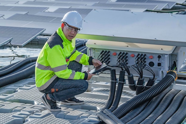 Ingeniero asiático trabajando en una central solar flotante Energía renovable Técnico e inversor de paneles solares comprobando los paneles en una instalación de energía solar