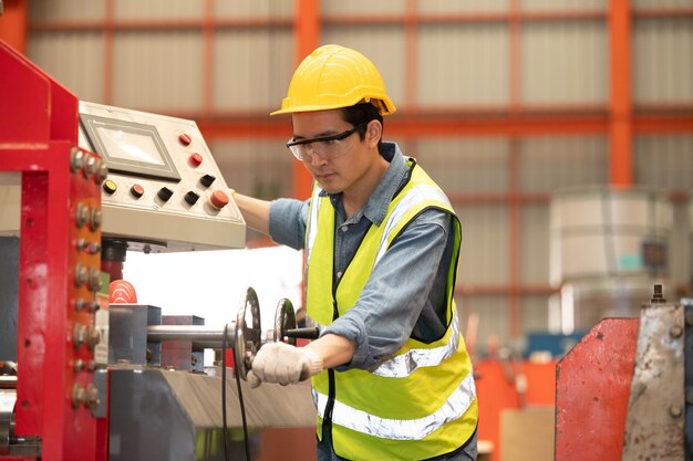 Ingeniero asiático trabajando duro en la fábrica de máquinas de control de seguridad de cascos de empleados de trabajadores de fábricas