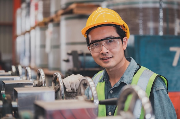 Ingeniero asiático trabajando en fábrica con máquina. La habilidad técnica es producción industrial de trabajo.