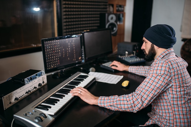 Ingeniero de audio trabaja con teclado musical en estudio. Tecnología de grabación de sonido digital profesional