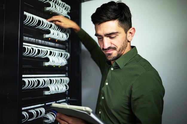 Foto ingeniero de cable y centro de datos con una tableta para mantenimiento de programación y actualización de software técnico de ti masculino con tecnología en la sala de servidores para hardware de cable o conexión a internet