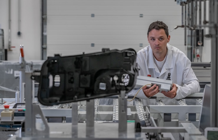 Foto el ingeniero de calidad realiza mediciones 3d de piezas de fundición de plástico con la ayuda de un robot para la industria automotriz.