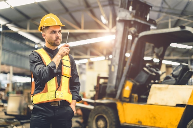 Foto ingeniero capataz usando radio walkie talkie operar control cargando carga en retrato de almacén confiado