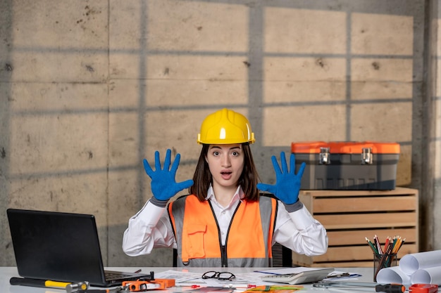 Foto ingeniero en casco y chaleco trabajador civil inteligente joven linda chica morena conmocionado