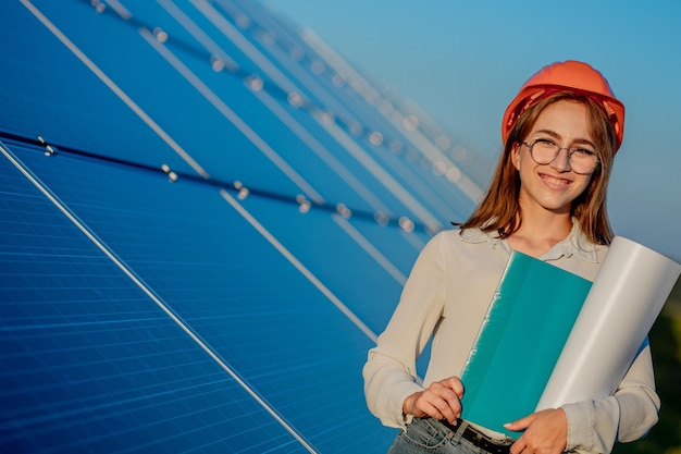 Ingeniero con casco naranja sonriendo y sosteniendo una carpeta, Green Energy Concept.