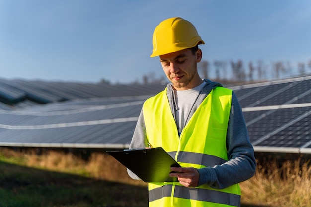Ingeniero caucásico con casco mirando los documentos y leyendo consejos del gobierno que trabaja en la construcción de una planta de energía solar