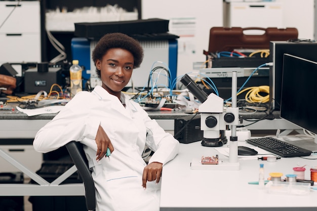 Ingeniero científico afroamericano en laboratorio con microscopio