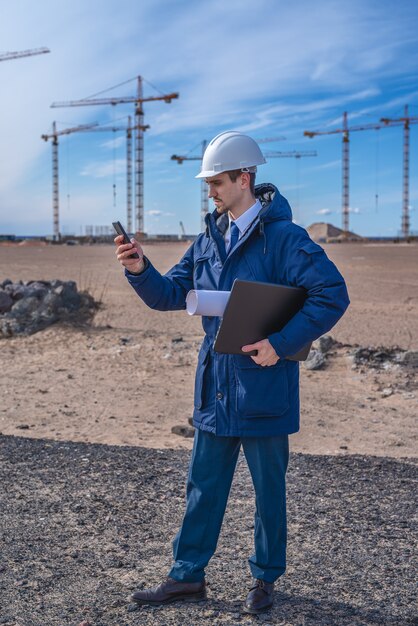 Ingeniero civil con casco blanco y chaqueta azul en el sitio