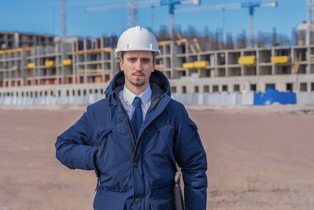 Ingeniero civil en un casco blanco, chaqueta de invierno en los edificios en construcción.