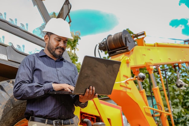 Ingeniero civil indio que trabaja en el sitio de construcción de edificios con construcción de grúas