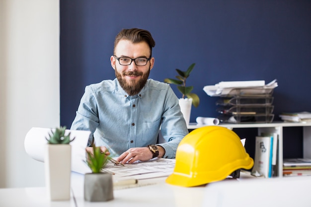 Foto ingeniero civil sonriente trabajando en plano en el lugar de trabajo