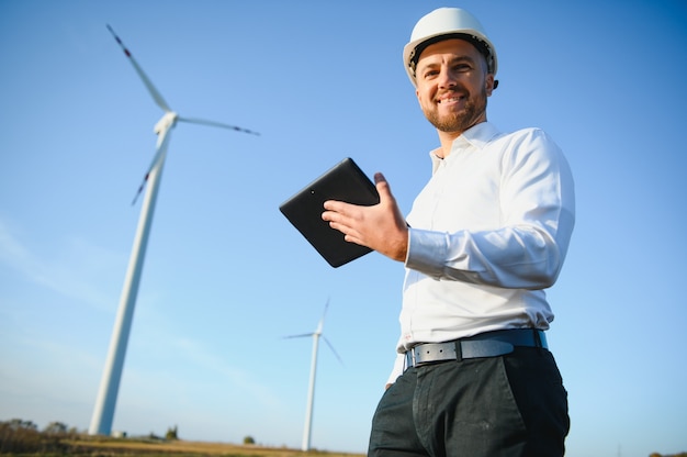 Foto el ingeniero está comprobando la producción de energía en la turbina eólica. trabajador en el parque de molinos de viento en casco.