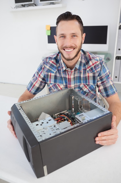 Foto ingeniero en computación sonriendo a la cámara al lado de la consola abierta