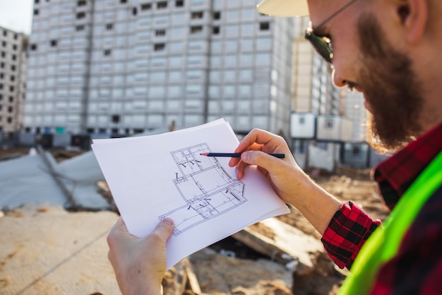 Ingeniero de construcción masculino. Arquitecto con un plano en un sitio de construcción