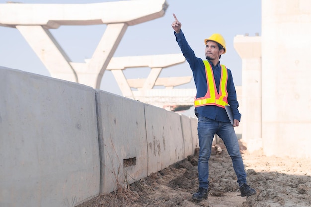 Ingeniero de construcción que usa inspección por computadora en la construcción de carreteras del sitio Trabajador de la construcción que usa una computadora portátil