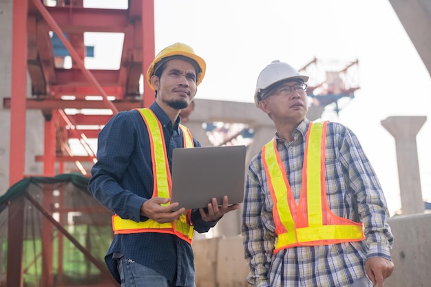 Ingeniero de construcción que usa inspección por computadora en la construcción de carreteras del sitio Trabajador de la construcción que usa una computadora portátil