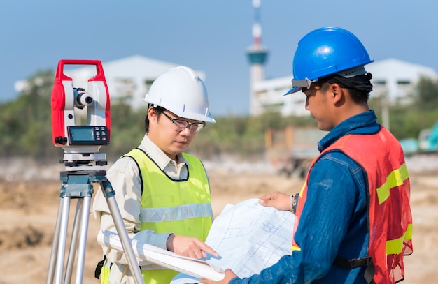 Ingeniero de construcción y trabajador capataz que verifica el dibujo de construcción en el sitio para el nuevo proyecto de construcción de infraestructura