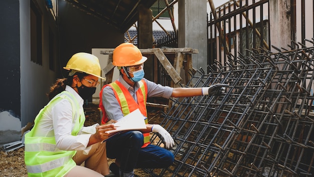 Ingeniero contratista reunión del equipo del trabajo del proyecto de la industria comprobar el diseño del plan de la casa en el sitio de construcción