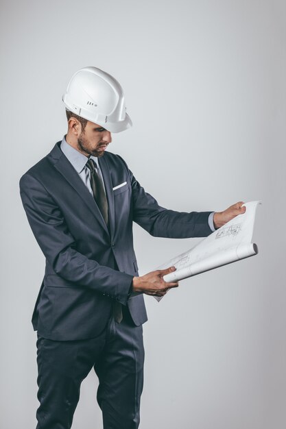 Ingeniero desenrollando y examinando borrador