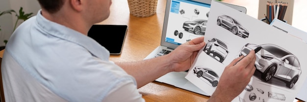Ingeniero de diseño de automóviles analiza el prototipo de automóvil para el negocio de automóviles en la oficina doméstica. El diseñador de ingeniería automotriz analiza cuidadosamente la búsqueda de fallas y mejoras para el diseño de automóviles con Synchronos portátiles.