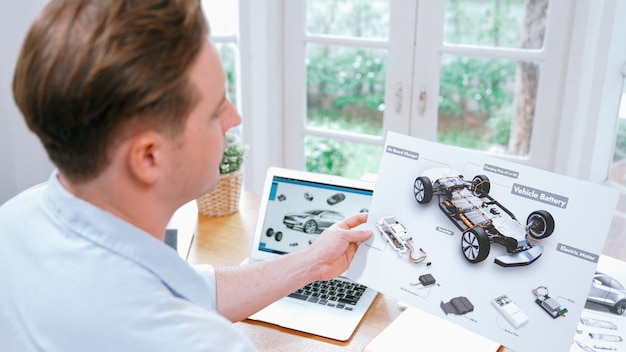 Ingeniero de diseño de automóviles analiza el prototipo de automóvil para el negocio de automóviles en la oficina doméstica. El diseñador de ingeniería automotriz analiza cuidadosamente la búsqueda de fallas y mejoras para el diseño de automóviles con Synchronos portátiles.