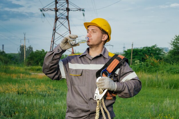 Ingeniero eléctrico, bebiendo agua para saciar su sed.