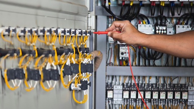 Foto ingeniero eléctrico comprobando el funcionamiento del armario de control eléctrico, concepto de mantenimiento.