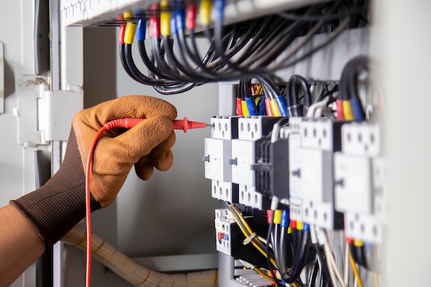 Foto el ingeniero eléctrico comprueba el sistema eléctrico midiendo con un multimetro