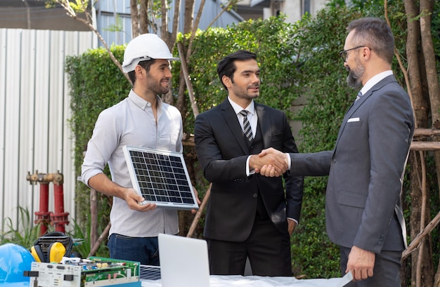 Ingeniero eléctrico con proyecto de acuerdo de apretón de manos de empresario panel de células solares en el edificio